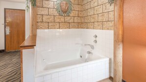 A bathroom with a white bathtub, tiled walls, and a wooden door. - Super 8 by Wyndham Dixon (Dixon)