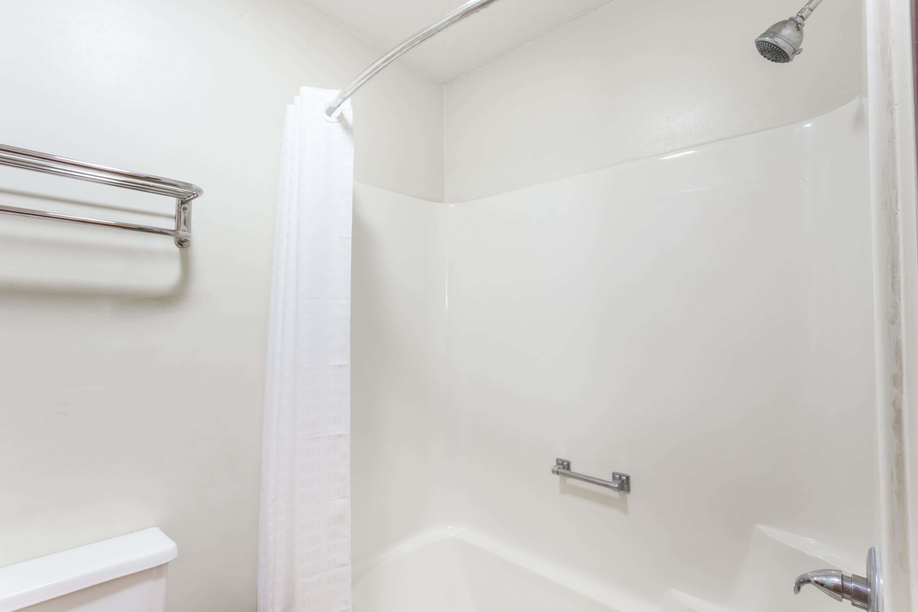 A shower area with a glass door, a metal towel rack, and a showerhead.