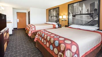 A hotel room with two beds, a cityscape view, a desk, and a patterned carpet.