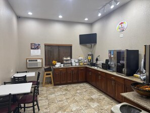 A small kitchenette with a coffee machine, a refrigerator, and a microwave. There is a window with blinds, a sink, and a small table with chairs. - Super 8 by Wyndham Mt. Vernon IL (Mount Vernon)