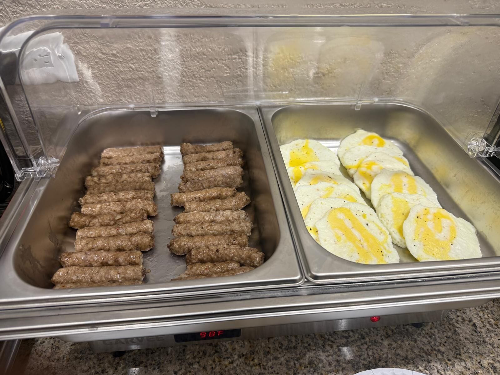 Un bufé con platos de carne y huevo.