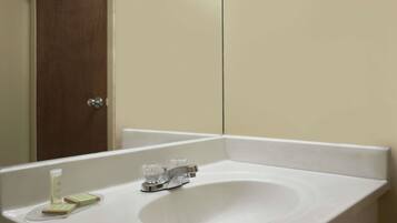A white bathroom sink with a mirror above it, a wooden door to the left, and a white countertop.