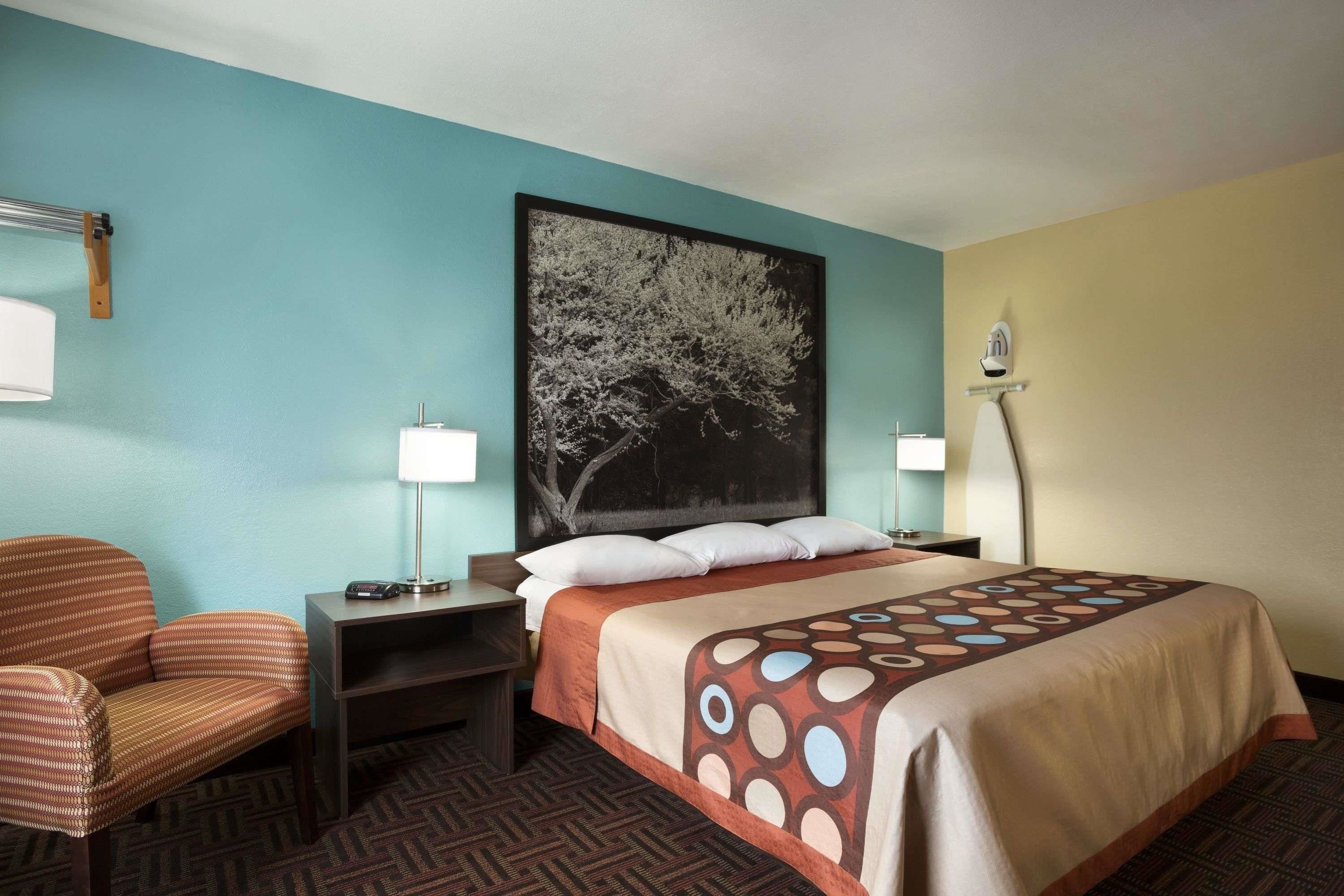 A hotel room with a bed, a chair, a desk, and a nightstand.