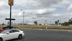 Un estacionamiento con un letrero de Super 8, un automóvil blanco y una camioneta.