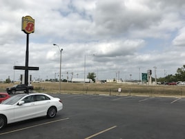 Un estacionamiento con un letrero de Super 8, un automóvil blanco y una camioneta.