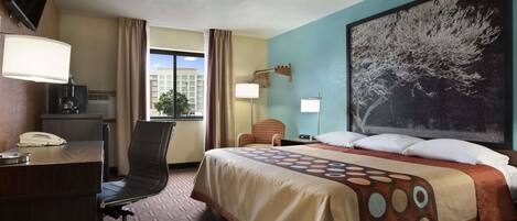 A hotel room with a bed, desk, chair, and a large window.