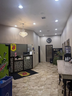 A reception area with a counter, a clock, and a chandelier.