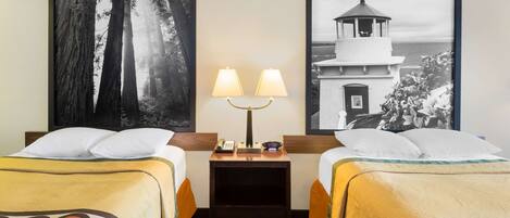 A hotel room with two beds, a nightstand with lamps, and two framed pictures on the wall.