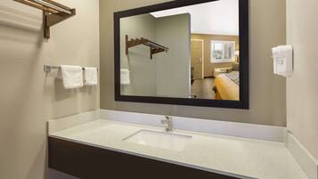 A bathroom with a white sink, a large mirror, and a towel rack.