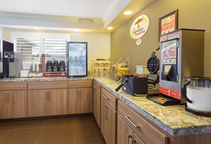 Start your day with a selection of freshly made waffles and coffee at our breakfast area, featuring a self-service beverage station and a variety of pastries.