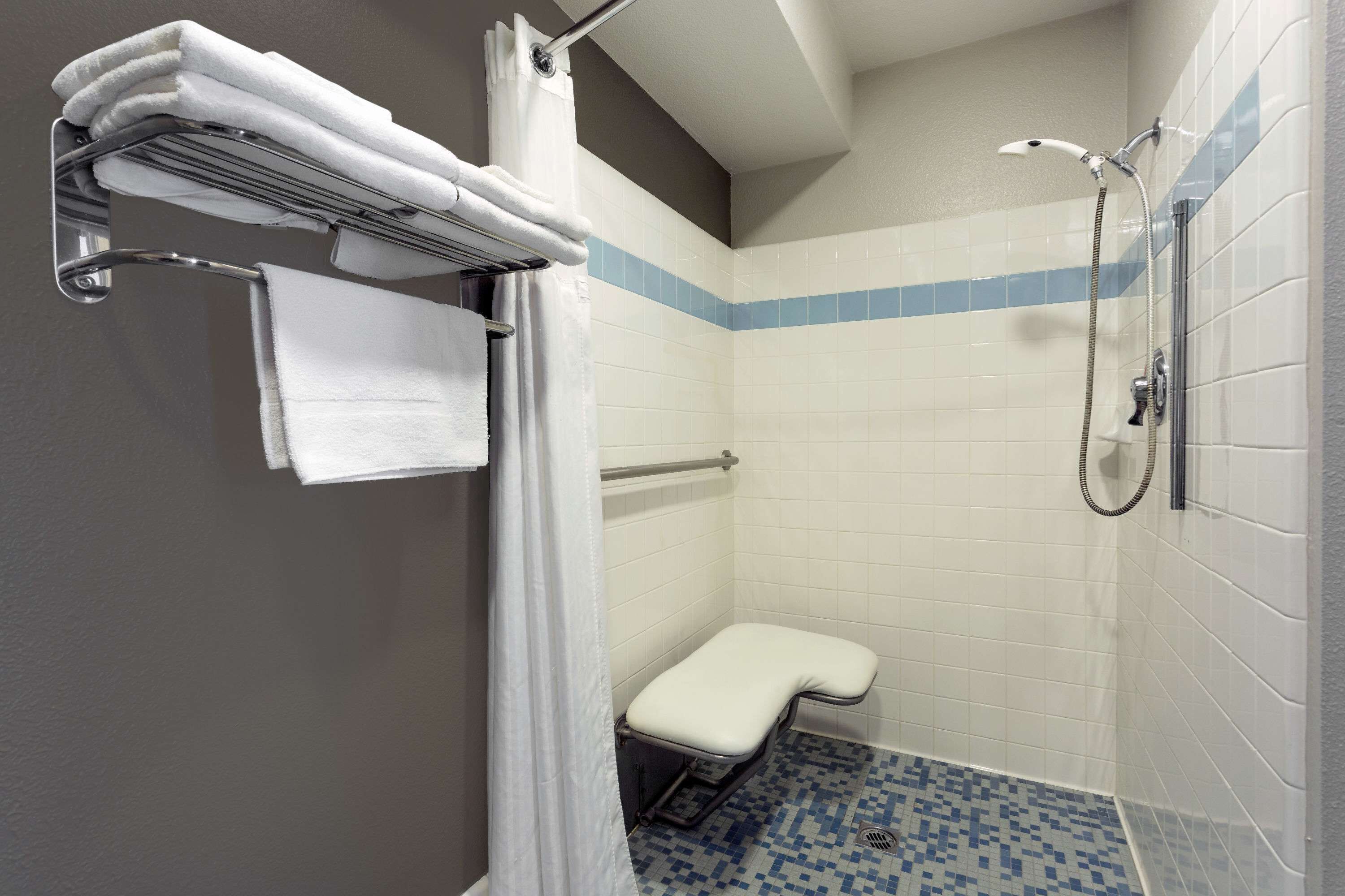 Un baño pequeño y moderno con ducha, un banco y un perchero para toallas.
