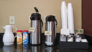 Een koffiehoek met een koffiezetapparaat, heetwaterdispenser en dispenser voor toevoegingen.