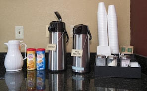 A coffee station with a coffee maker, hot water dispenser, and condiment dispensers. - Red Roof Inn Cookeville - Tennessee Tech (Cookeville)