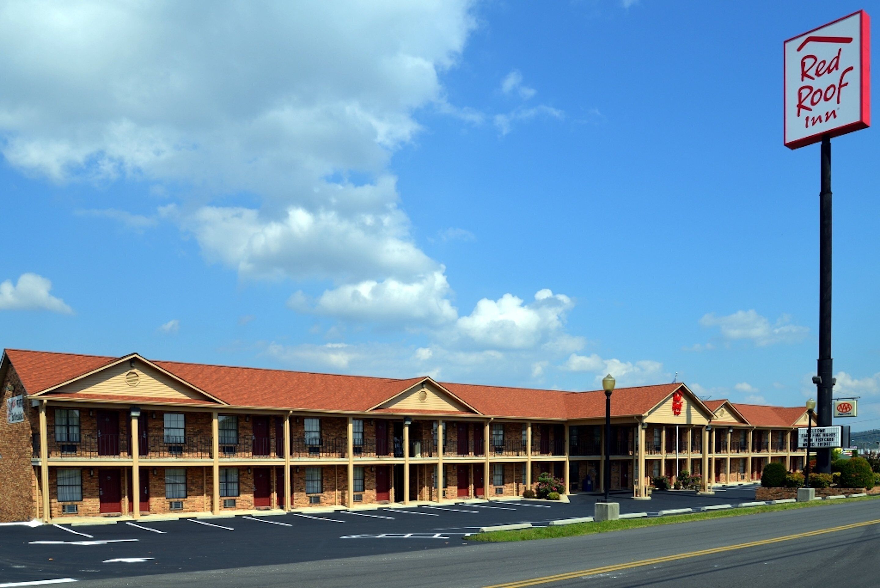 Un motel à deux étages, avec un toit rouge et de nombreuses chambres.