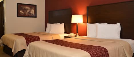 A hotel room with two beds, a nightstand with a lamp, a telephone, and a framed picture on the wall.