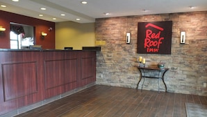 Een receptiegedeelte met een houten balie, een stenen muur en een Red Roof Inn bord.
