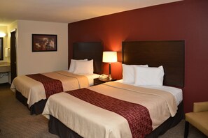 A hotel room with two beds, a nightstand with a lamp, a telephone, and a painting on the wall. - Red Roof Inn Cookeville - Tennessee Tech (Cookeville)