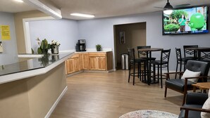 Una cocina moderna con armarios de madera, una cafetera y un televisor montado en la pared.