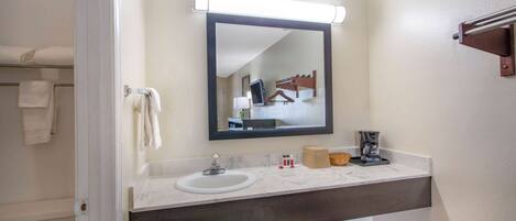 A bathroom with a sink, mirror, towel rack, and a towel hanging on the wall.