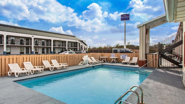 A swimming pool with lounge chairs and a building with a sign reading "BAYMONT". - Super 8 by Wyndham Florence (Florence)