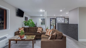 A modern living room with a sectional sofa, a coffee table, and a flat-screen TV mounted on the wall. - Super 8 by Wyndham Florence (Florence)