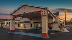A motel with a covered parking area, a gas station sign, and a row of rooms with balconies. - Super 8 by Wyndham Florence (Florence)