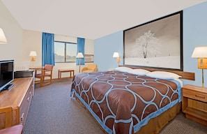 A hotel room with a large bed, a desk with a TV, a chair, and a window with curtains. - Super 8 by Wyndham Centerville (Centerville)