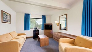 A hotel room with a sofa, a small wooden table, a TV, and a dresser. - Super 8 by Wyndham Centerville (Centerville)