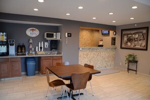 A modern kitchen with a dining area, granite countertops, and a stone backsplash.