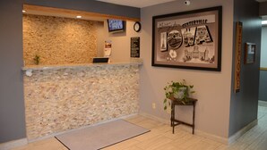 A reception area with a mosaic wall, a clock, a framed welcome sign, and a small table with a plant. - Super 8 by Wyndham Centerville (Centerville)
