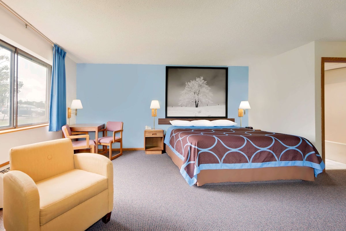 A hotel room with a bed, a chair, a desk, and a nightstand.