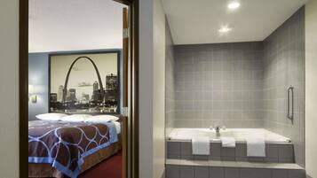 A hotel room with a bed, a cityscape mural, and a bathroom with a bathtub and tiled walls.