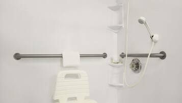 A bathroom with a white toilet, a grab bar, a showerhead, and a towel rack.