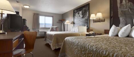 A hotel room with two beds, a desk, a chair, a TV, and a large painting on the wall.