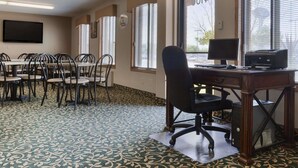 Un salón de conferencias con una amplia mesa, varias sillas, un escritorio con monitor e impresora, y alfombra estampada.
