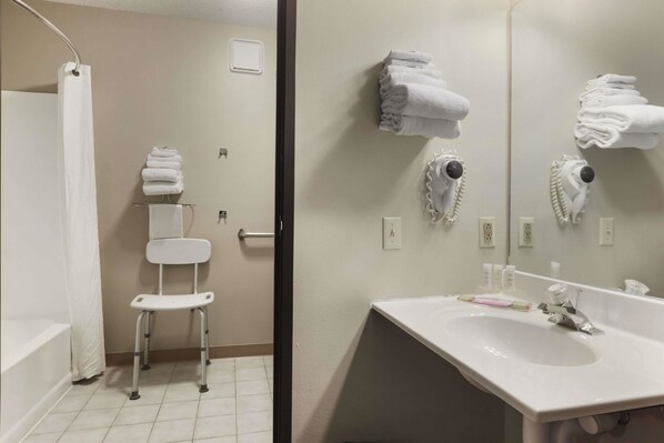 Un baño con lavamanos blanco, un espejo y zona de ducha.