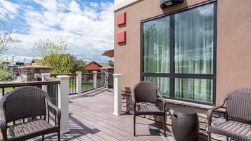Eine Terrasse mit Korbmöbeln und einem großen Fenster.