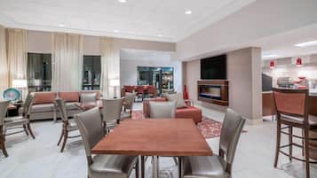 A modern living room with a dining area, a TV, and a kitchen.