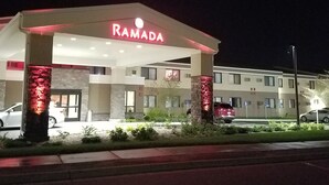 A Ramada hotel with a modern facade, illuminated signage, and a parking area with several cars. - Ramada by Wyndham Minneapolis Golden Valley (Golden Valley)