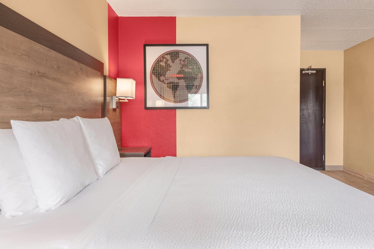 A hotel room with a large bed, a wall-mounted globe, a nightstand, and a door.
