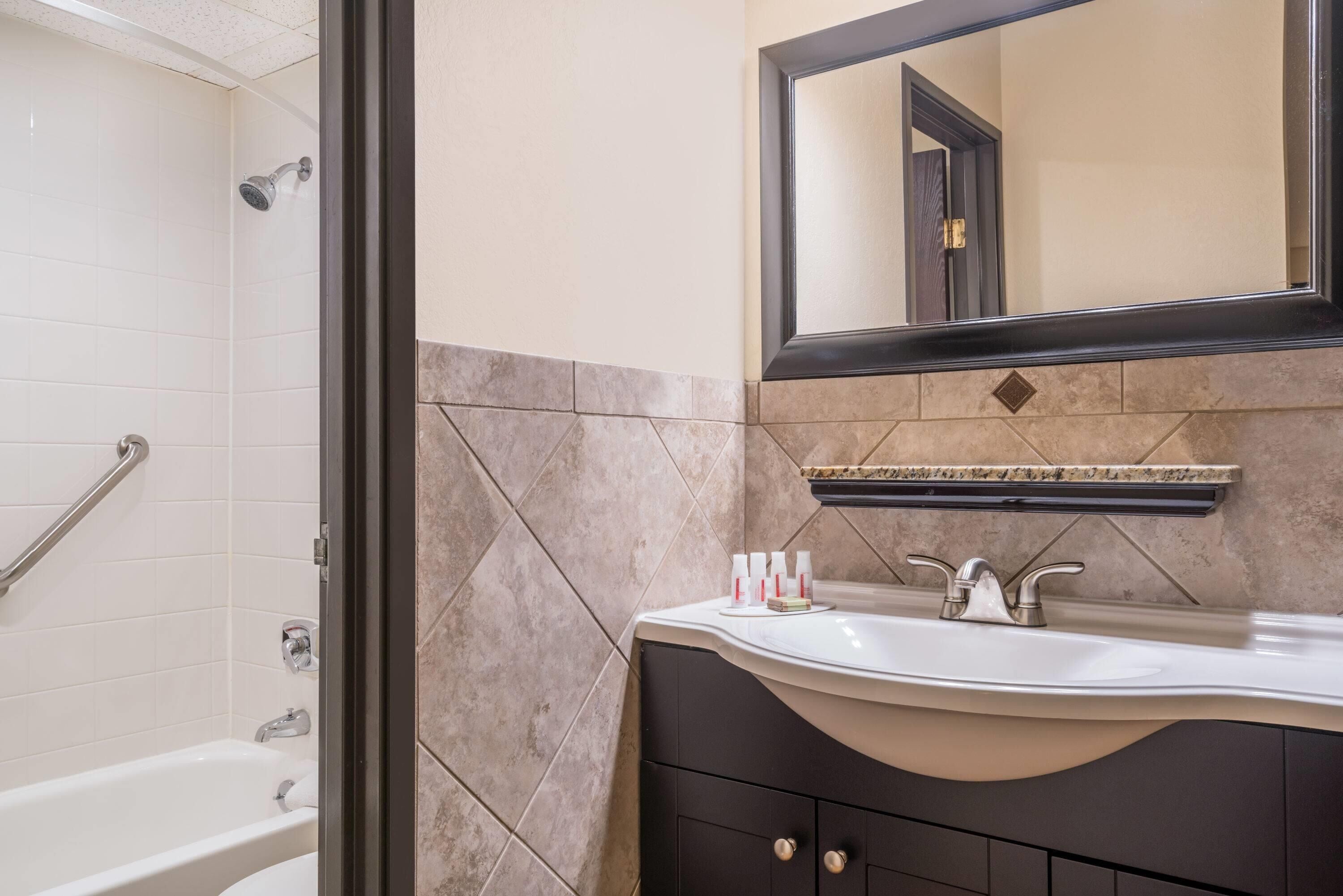 A bathroom with a bathtub, a sink, and a mirror.