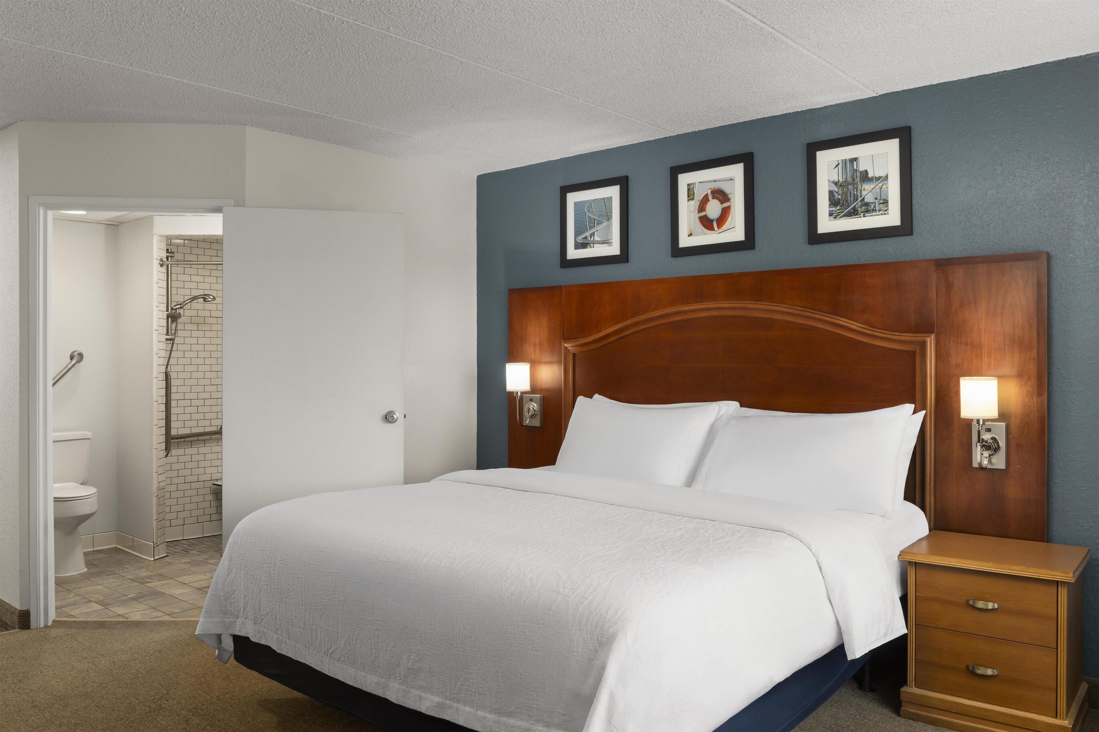 Una habitación de hotel con una cama grande, un cabecero de madera, dos lámparas de noche y una mesita de noche.