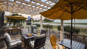 An outdoor patio with seating, a fire pit, and umbrellas. - Harbor Town, BW Signature Collection (Manitowoc)