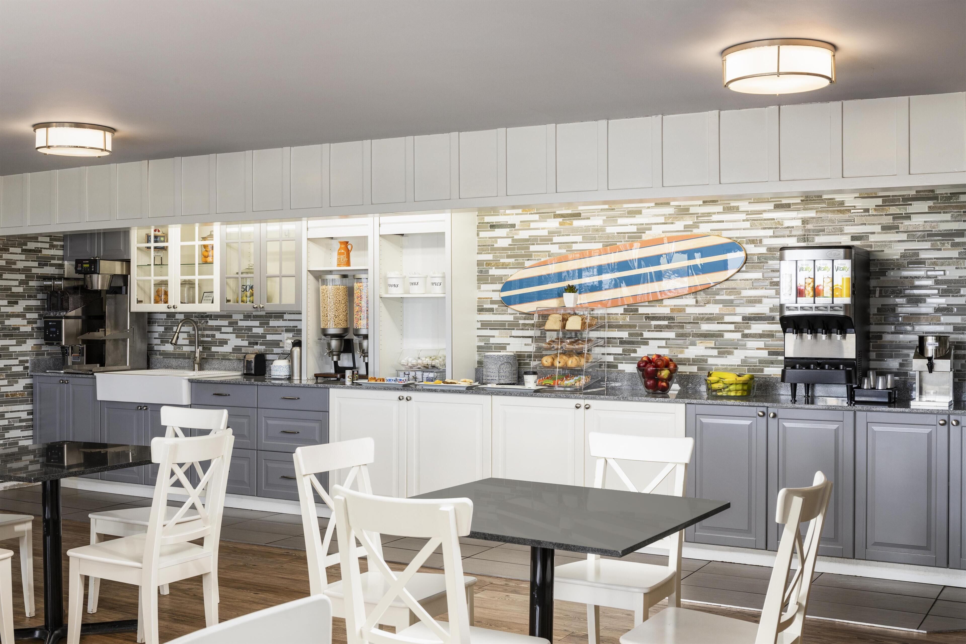 Una cocina moderna con armarios blancos, encimera negra y una decoración con una tabla de surf.
