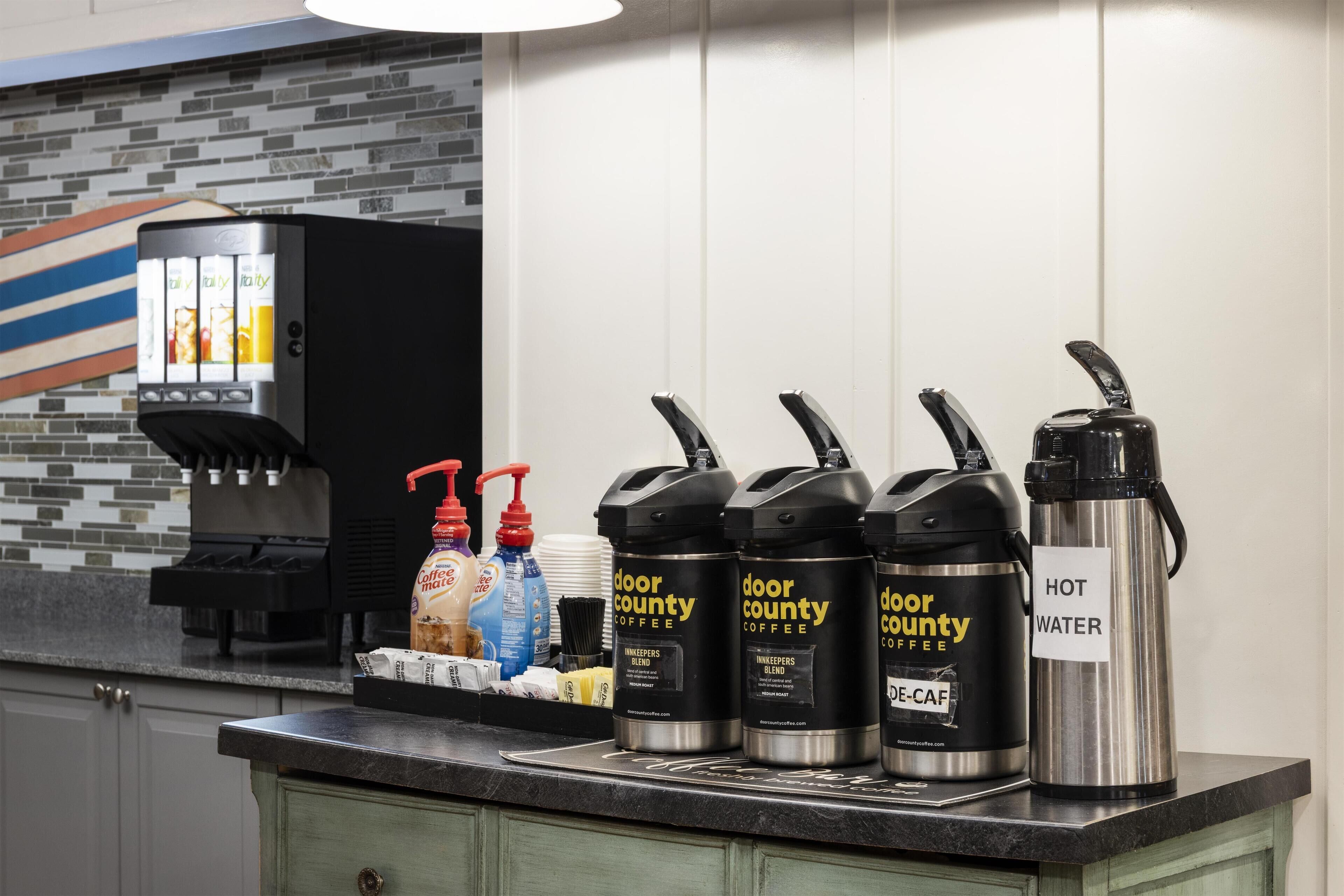 A coffee station with multiple coffee dispensers labeled "Door County Coffee," a coffee machine, and a water dispenser.