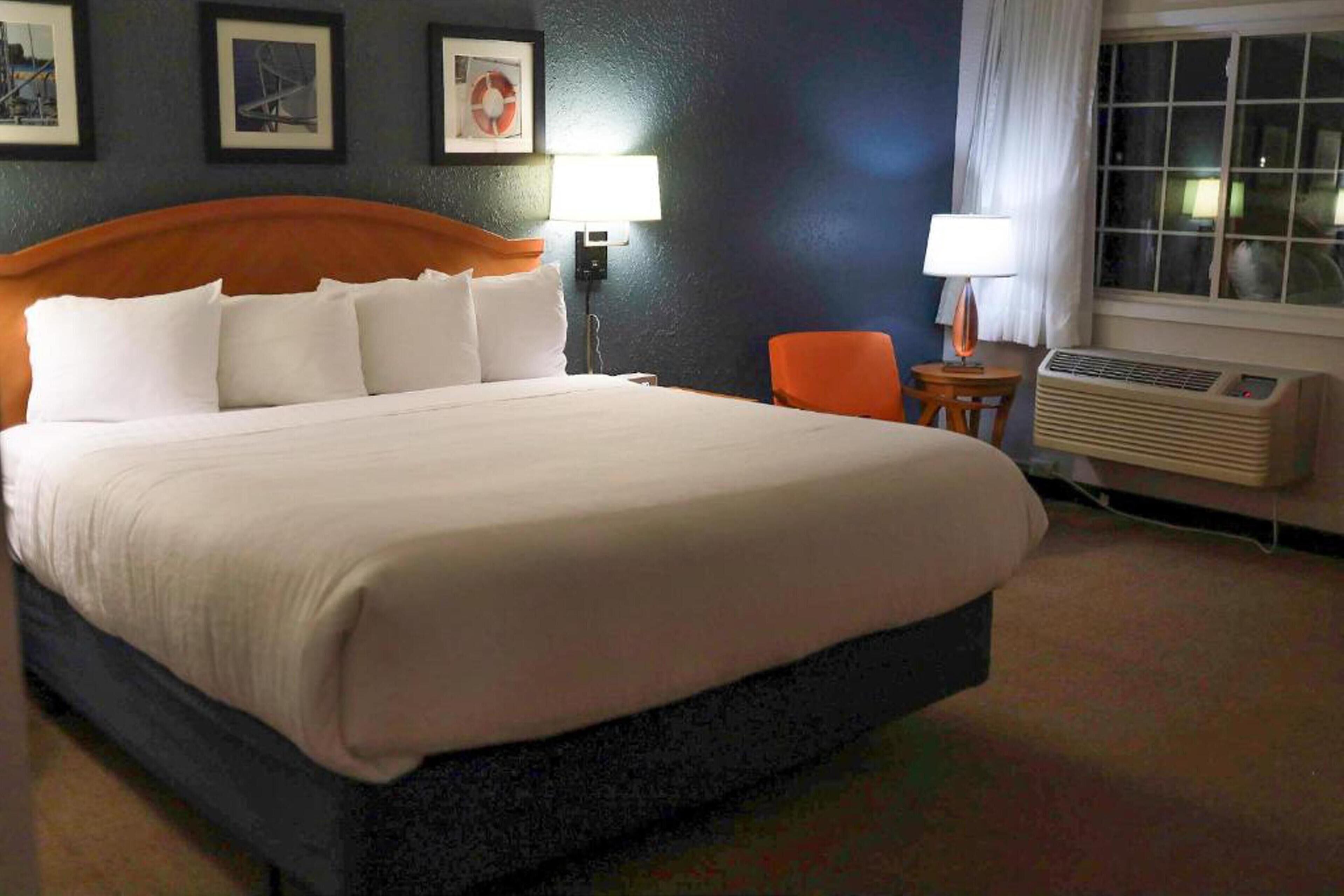 A hotel room with a large bed, a chair, a table, and a window.