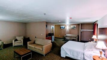 A hotel room with a bed, a sofa, a small table, and a TV.