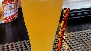 Una jarra alta de cerveza con espuma, sobre una superficie de metal perforado.
