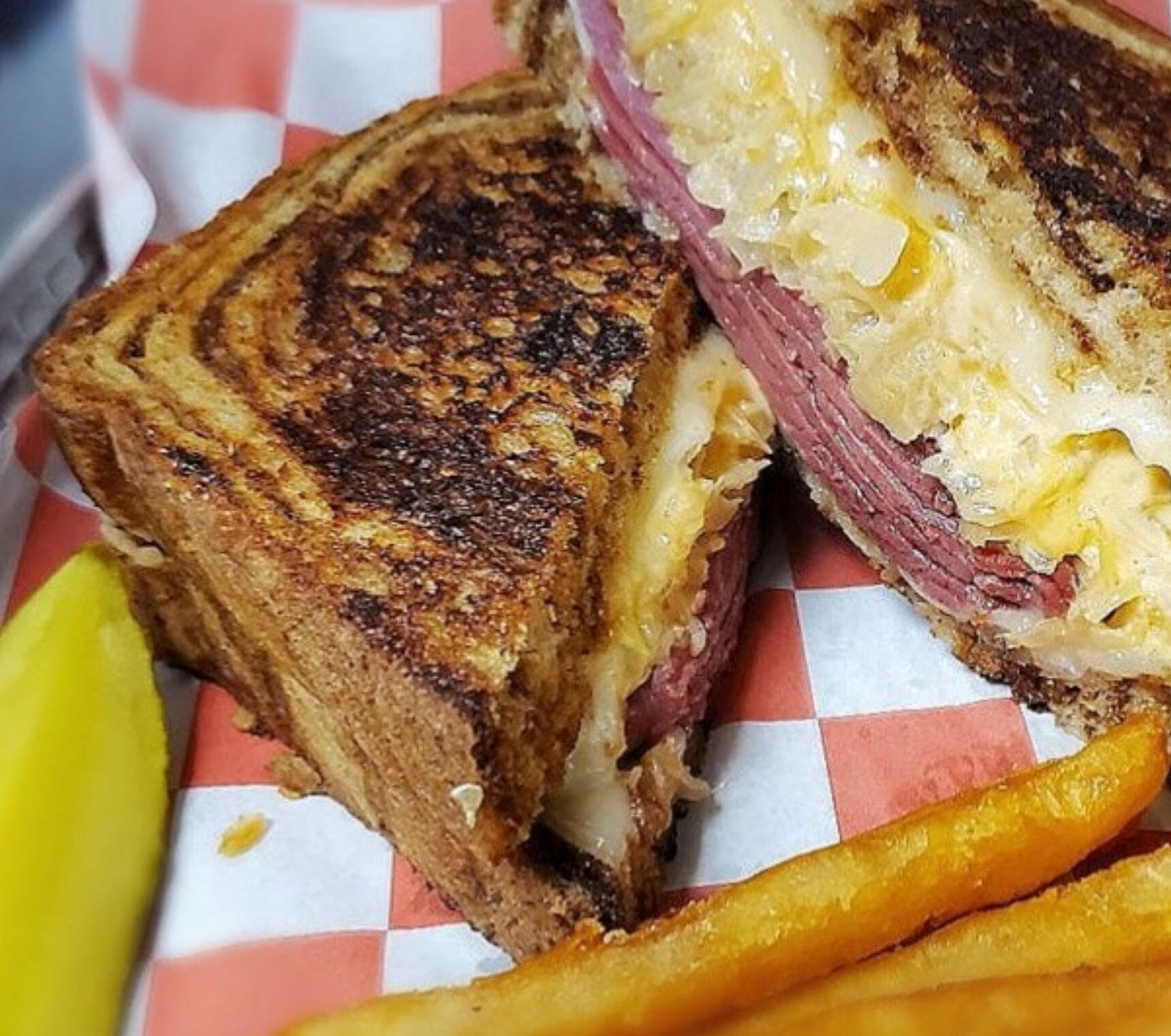 A grilled sandwich with fries and a pickle.