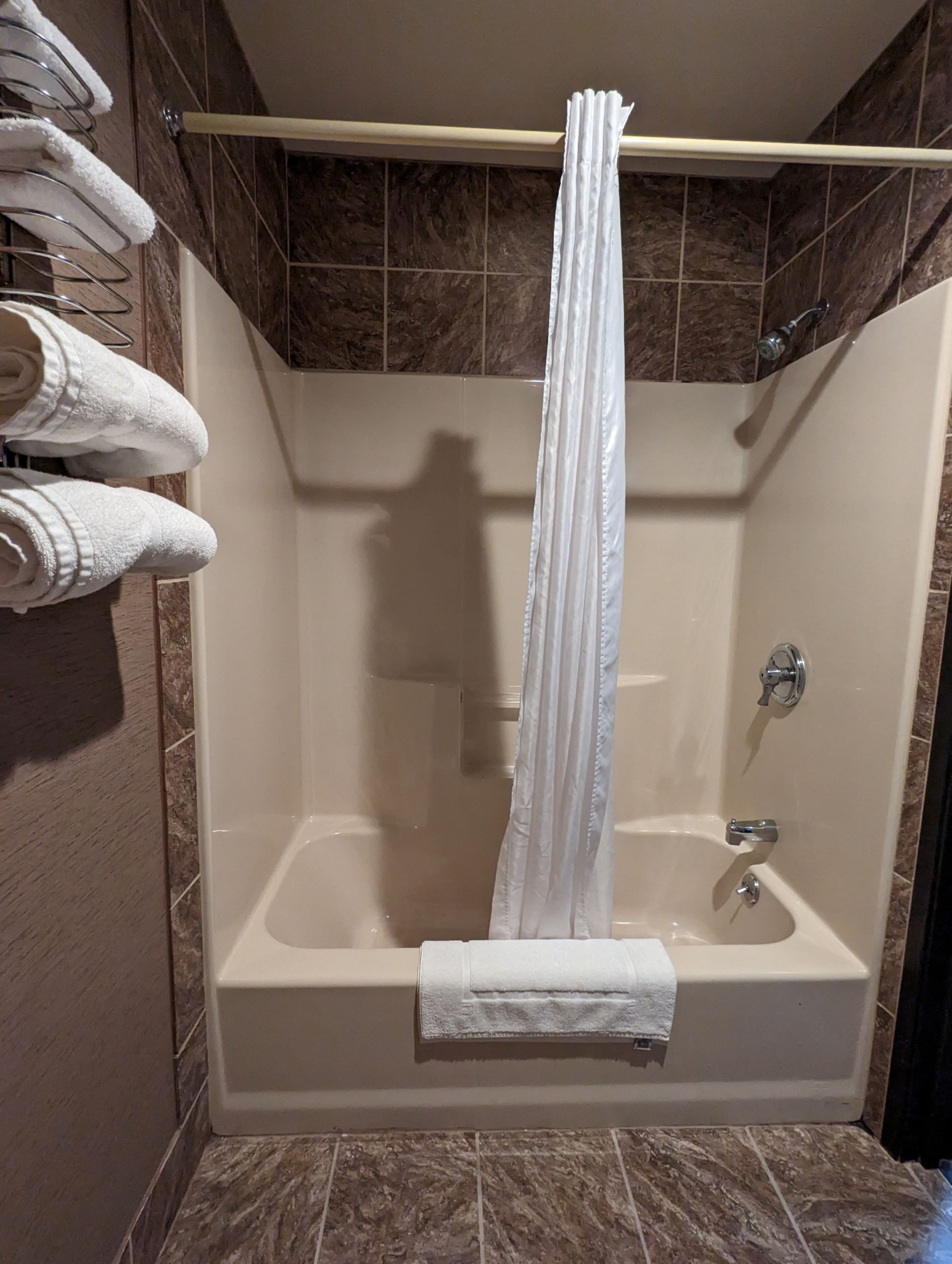 Une salle de bain avec une baignoire, un porte-serviettes avec des serviettes pliées et un rideau de douche.